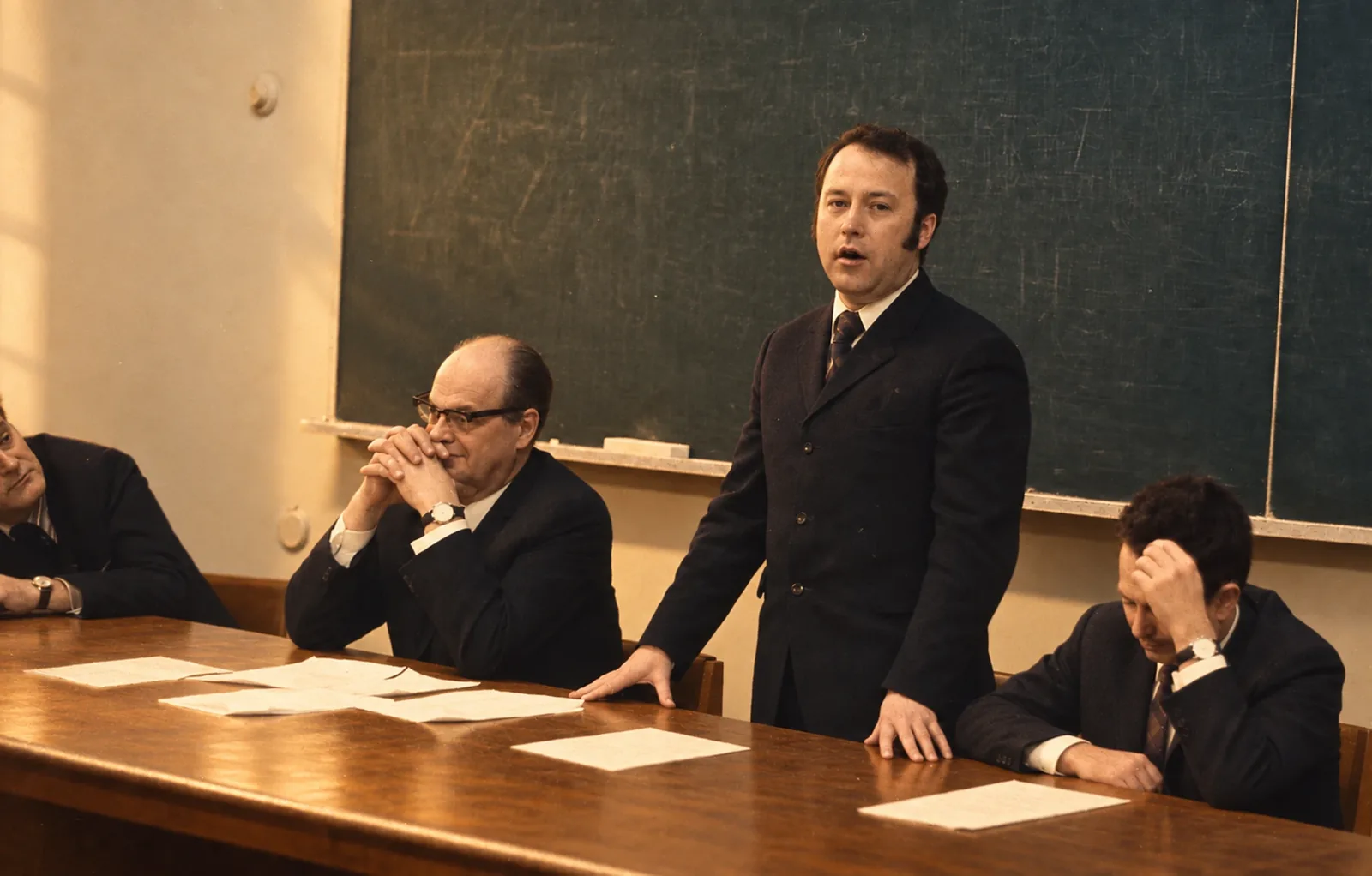 Historical scientific meeting with Aleksandr Prokhorov, Nikolay Basov, Anatoliy Oraevsky and Yuri Popov seated and standing around a conference table before a chalkboard.